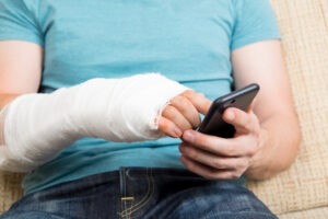 An injured man with his arm in a cast, calling an experienced personal injury lawyer in Enfield.