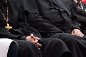 priests sitting with hands in laps
